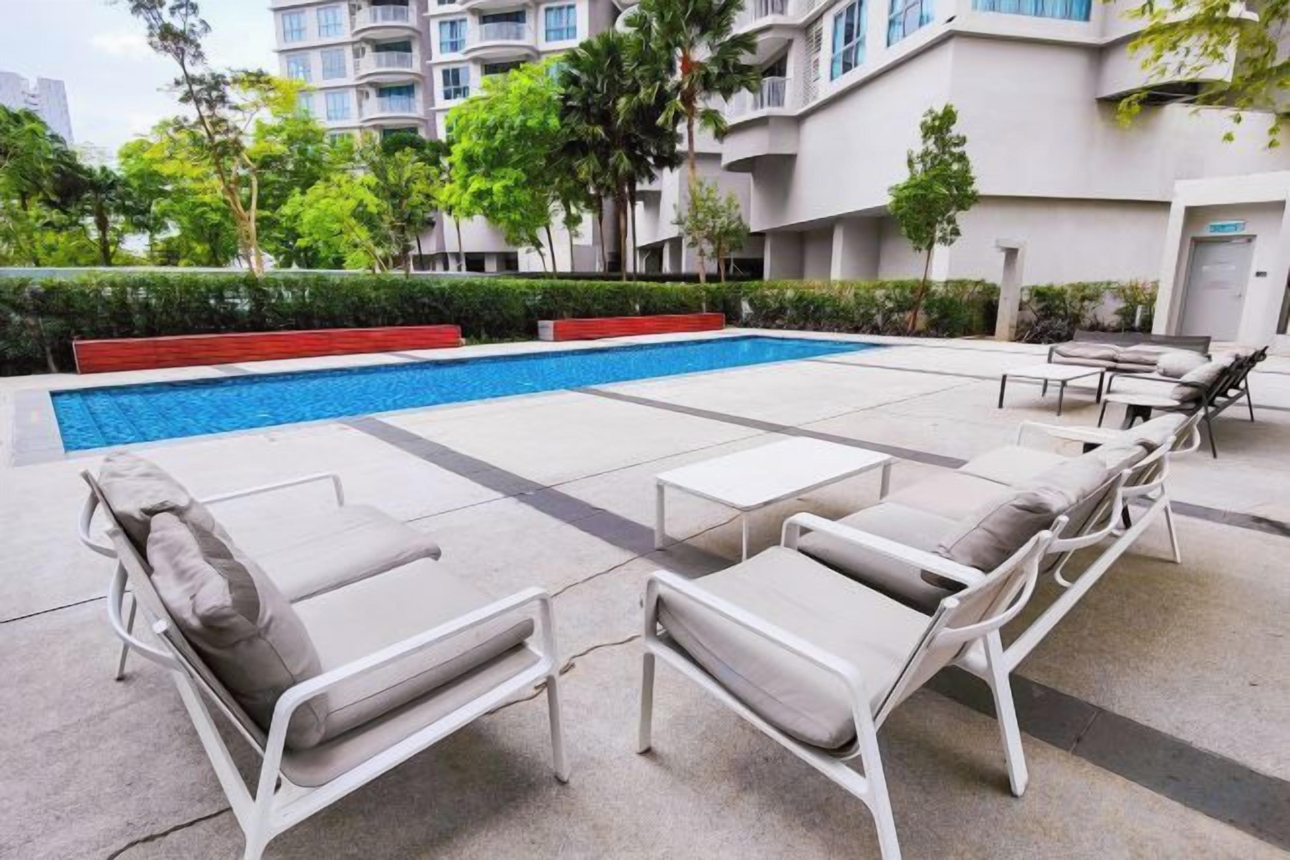 A swimming pool area with lounge chairs and a small table.