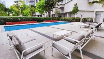 A swimming pool area with lounge chairs and a small table.