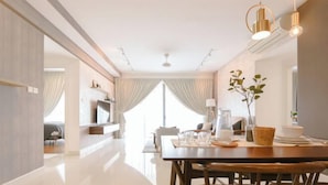 A modern dining area with a wooden table, chairs, and a chandelier. - Teega Suites by RR JBcity (Iskandar Puteri)