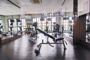 Uma academia com diversos equipamentos de exercício, janelas amplas e design moderno e limpo.