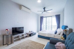 Une chambre moderne avec un lit, une télévision, un ventilateur de plafond et une fenêtre avec des rideaux.