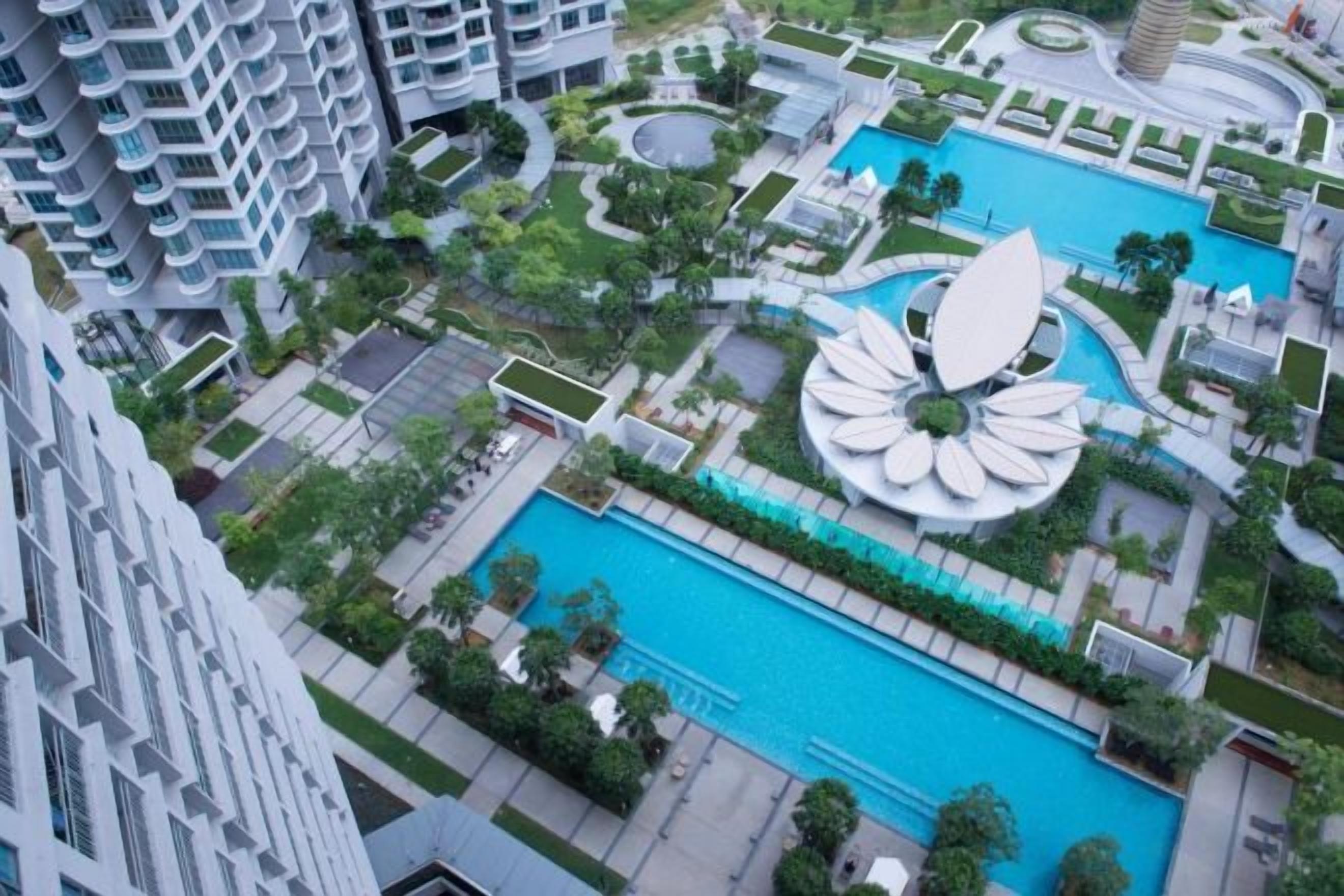 Un quartier résidentiel doté d’une piscine centrale, entouré de verdure et de bâtiments modernes.