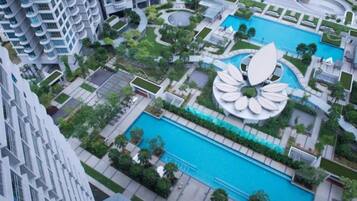 Un quartier résidentiel doté d’une piscine centrale, entouré de verdure et de bâtiments modernes.