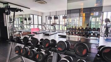Une salle de sport équipée de machines d’exercice, de supports pour les poids, de tapis de course et d’un mur recouvert de miroirs.