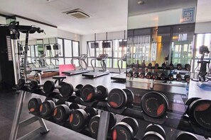 Ein Fitnessstudio mit Trainingsgeräten, Gewichtsständern, Laufbändern und einer Spiegelwand.