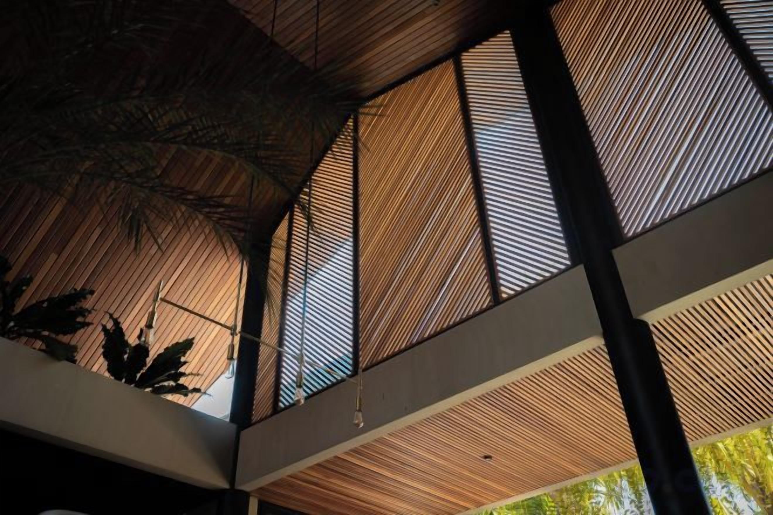 A modern interior with a geometric ceiling structure and vertical wooden slats.