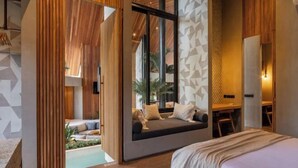 A modern bedroom with a large window, a built-in seating area, and a desk. - Award-Winning 3BR Villa 25m Pool Villa FEH (Bali)