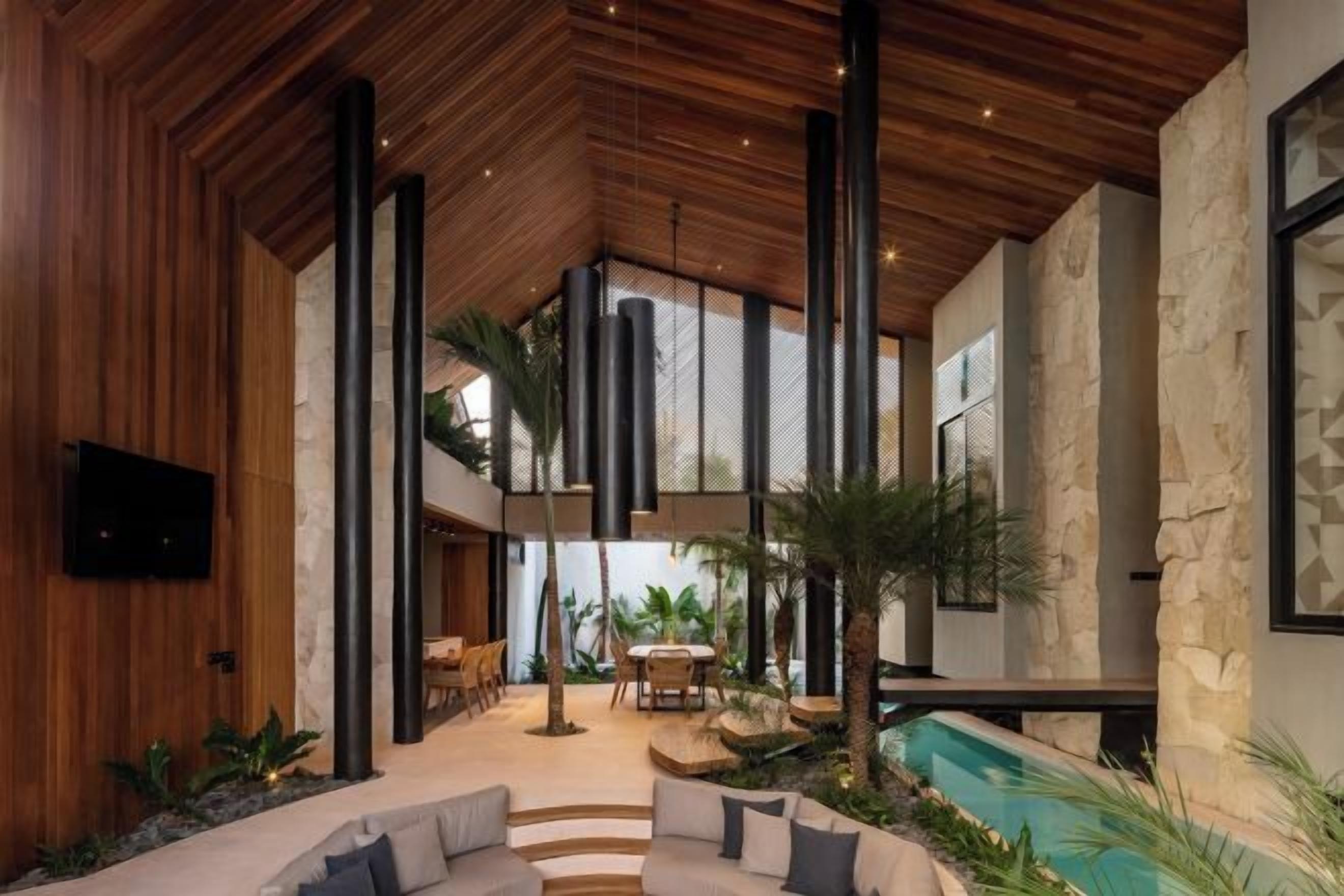 A modern interior with a wooden ceiling, stone walls, a seating area, and a pool.