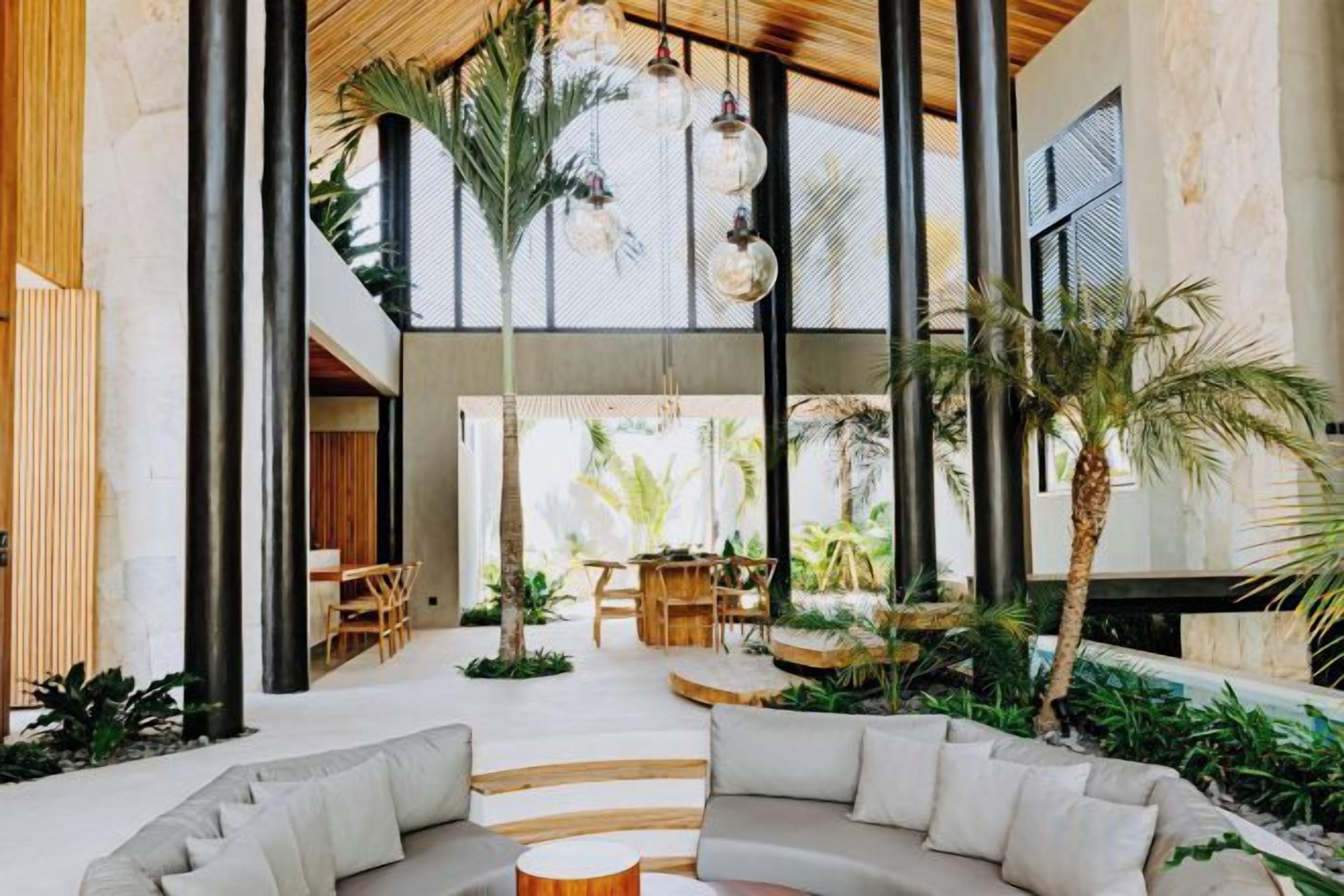A spacious indoor area with a modern design, featuring a large seating area, a dining setup, and a view of the outdoors.