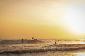 Escena de playa con olas y gente.