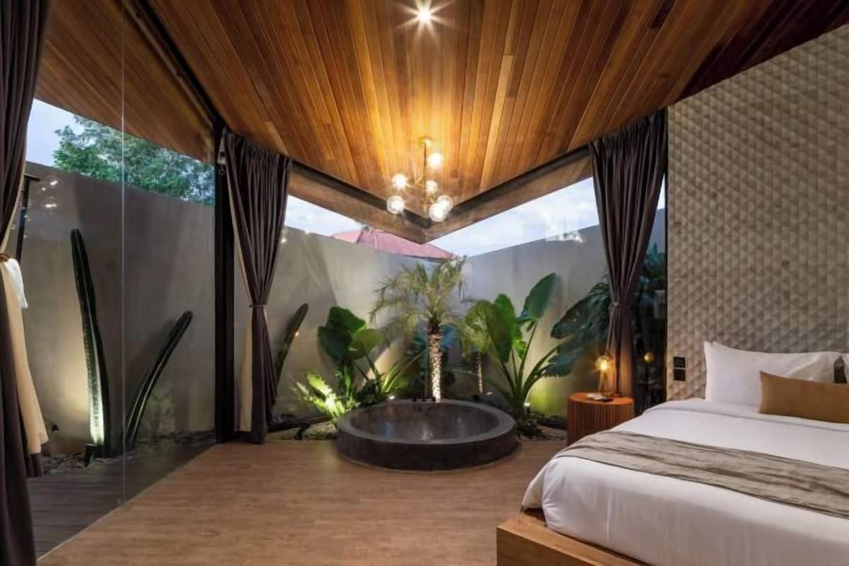 Une chambre moderne avec un plafond en bois, une fontaine circulaire et un lit donnant sur un paysage verdoyant.
