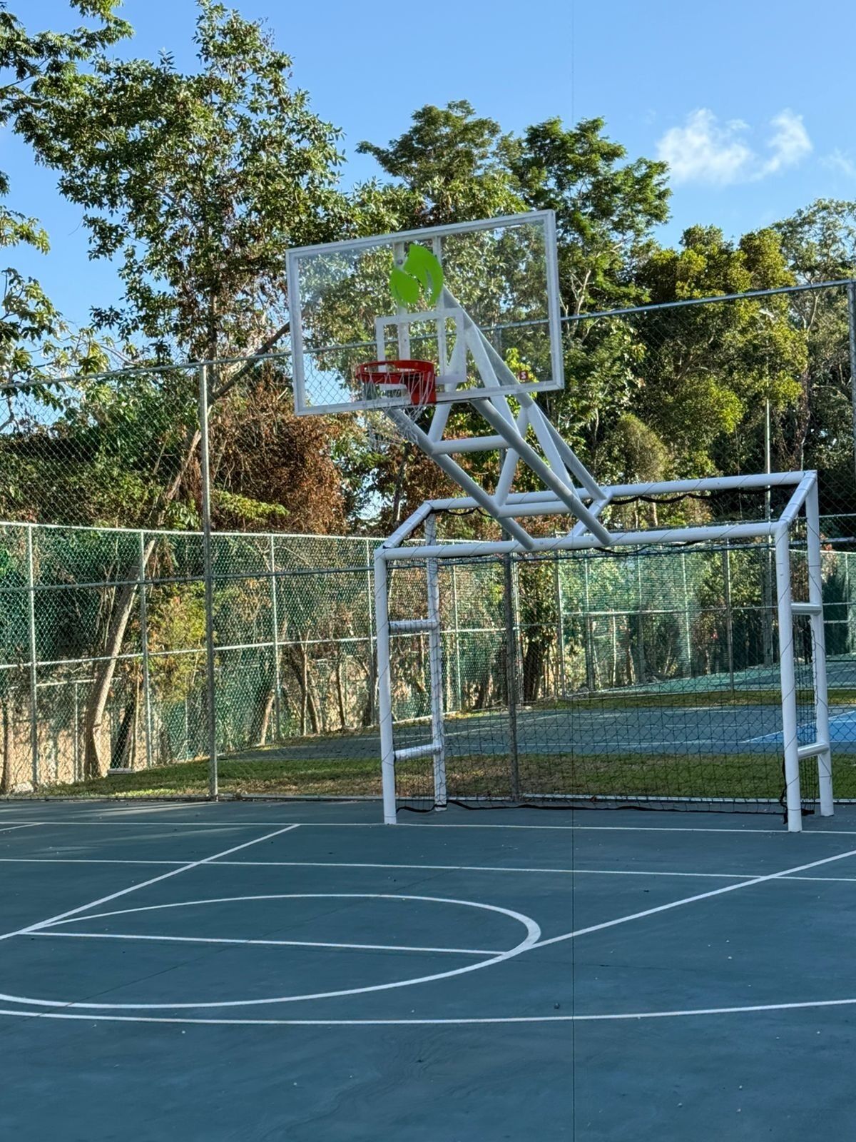 A basketball court with a hoop and a chain-link fence.