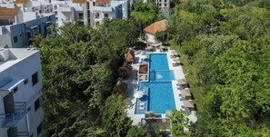 An aerial view of Selva Escondida II, featuring a resort-style living area with a swimming pool surrounded by lush greenery and modern buildings. - RESORT-STYLE IN PUERTO MORELOS. TECUN HOUSE (Puerto Morelos)