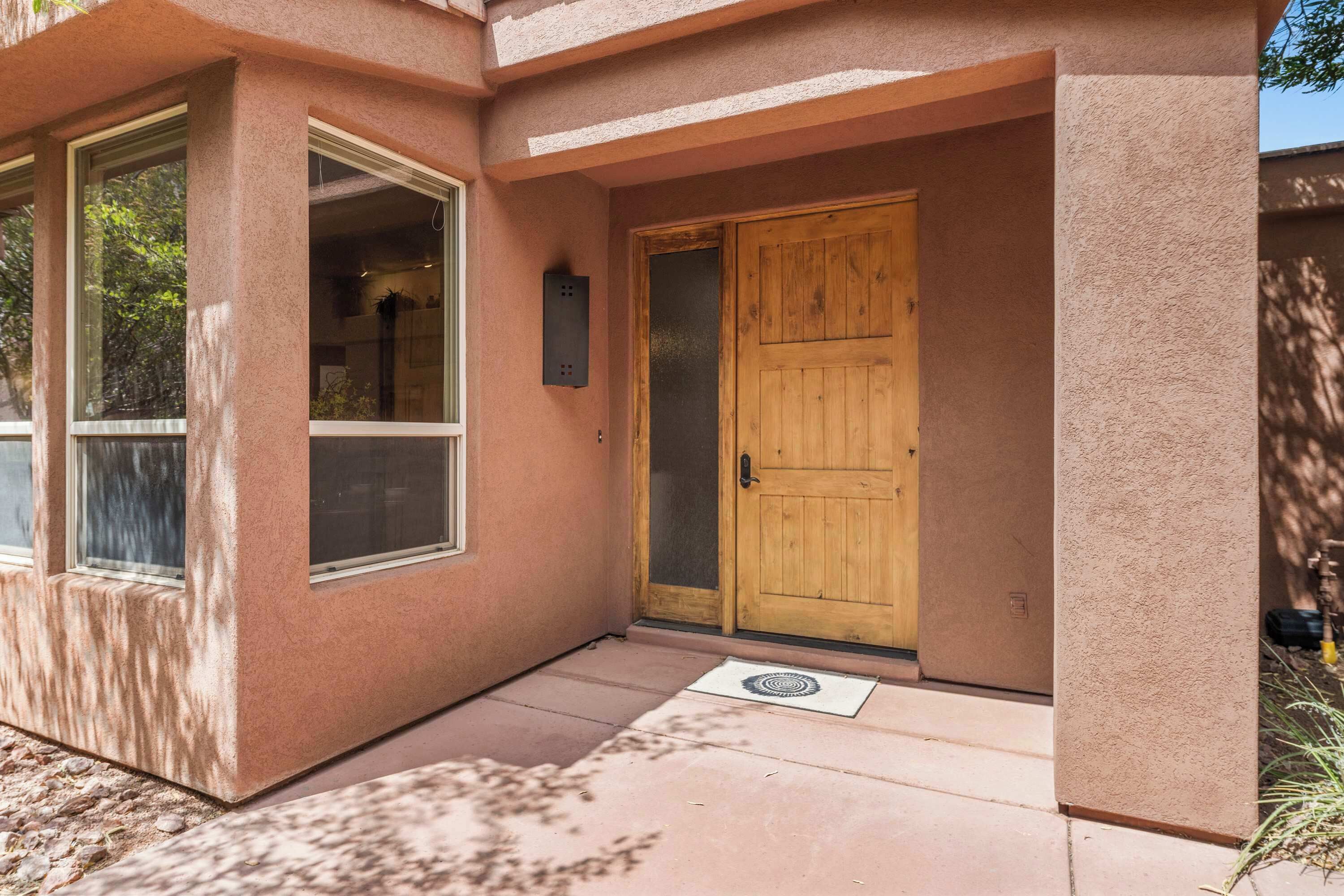 Una casa con puerta de madera, ventana y felpudo.