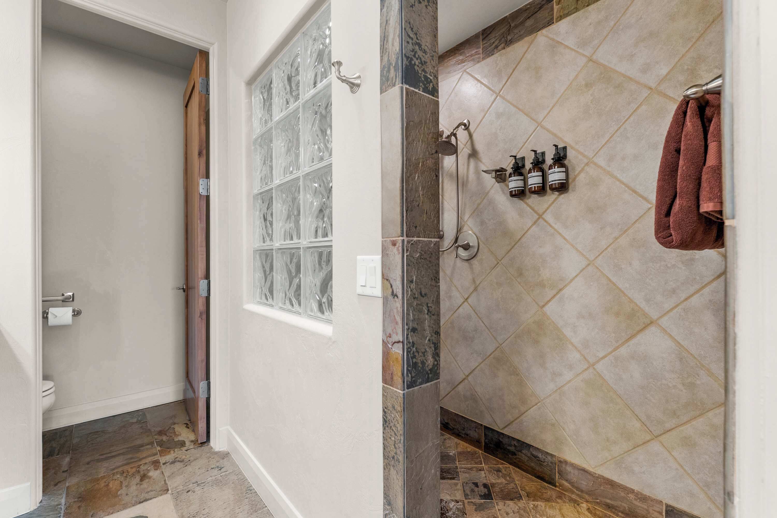 A bathroom with a shower, tiled walls, and a window.