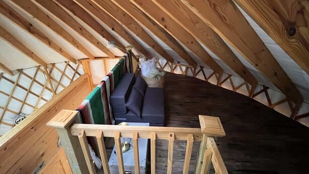 Une chambre aménagée sous les toits, avec un plafond en bois, un canapé intégré et une petite fenêtre.