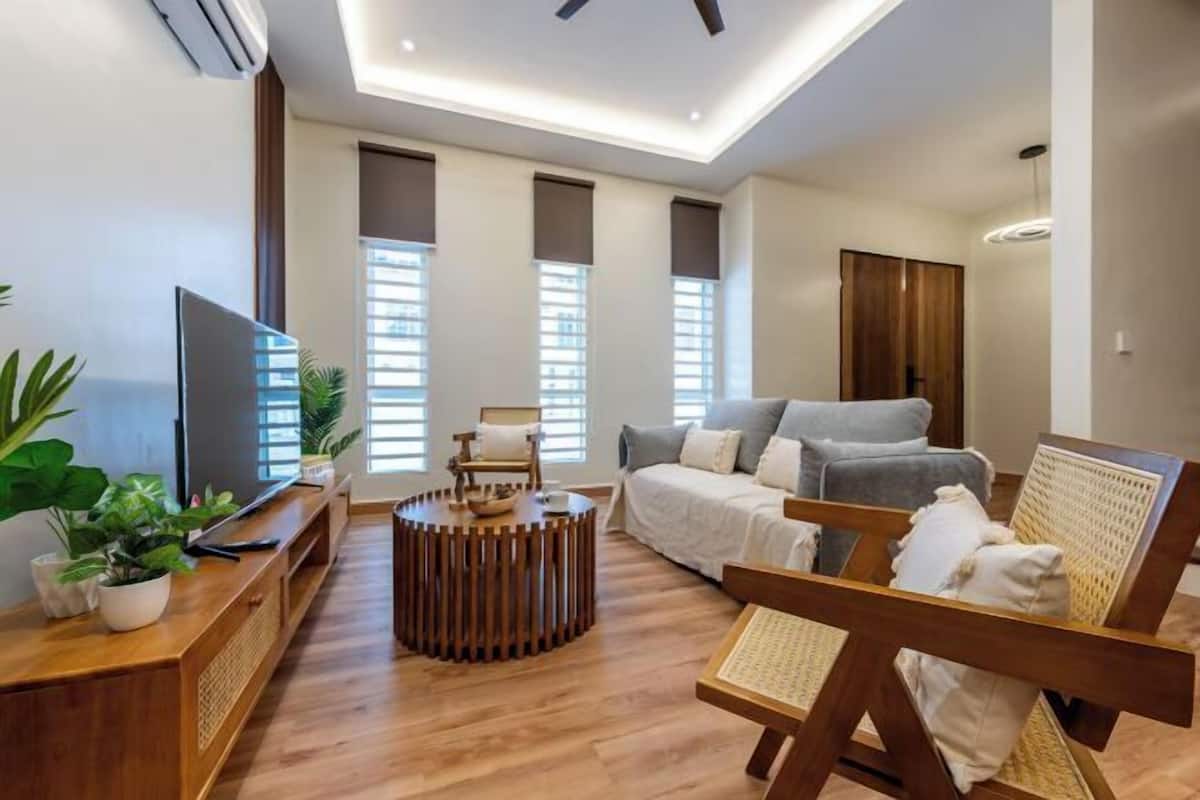 Ein modernes Wohnzimmer mit Couch, Fernseher auf einem Holzständer und einem Holztisch.