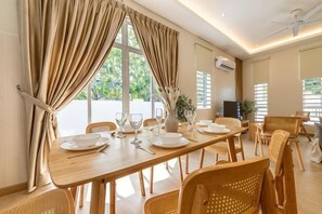 A dining area with a wooden table, chairs, and a view of greenery outside.