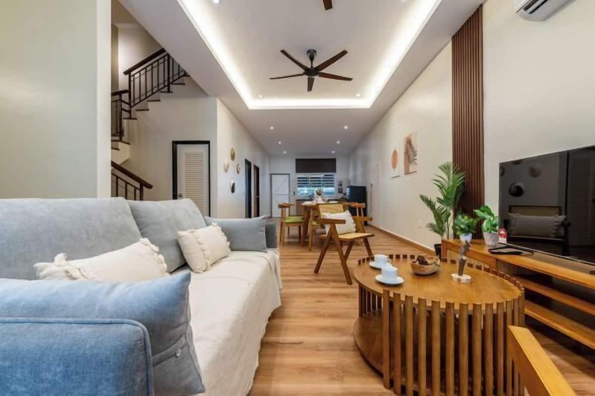 Ein modernes Wohnzimmer mit einer Couch, einem Holzesstisch, einem Deckenventilator und einem Fernseher.