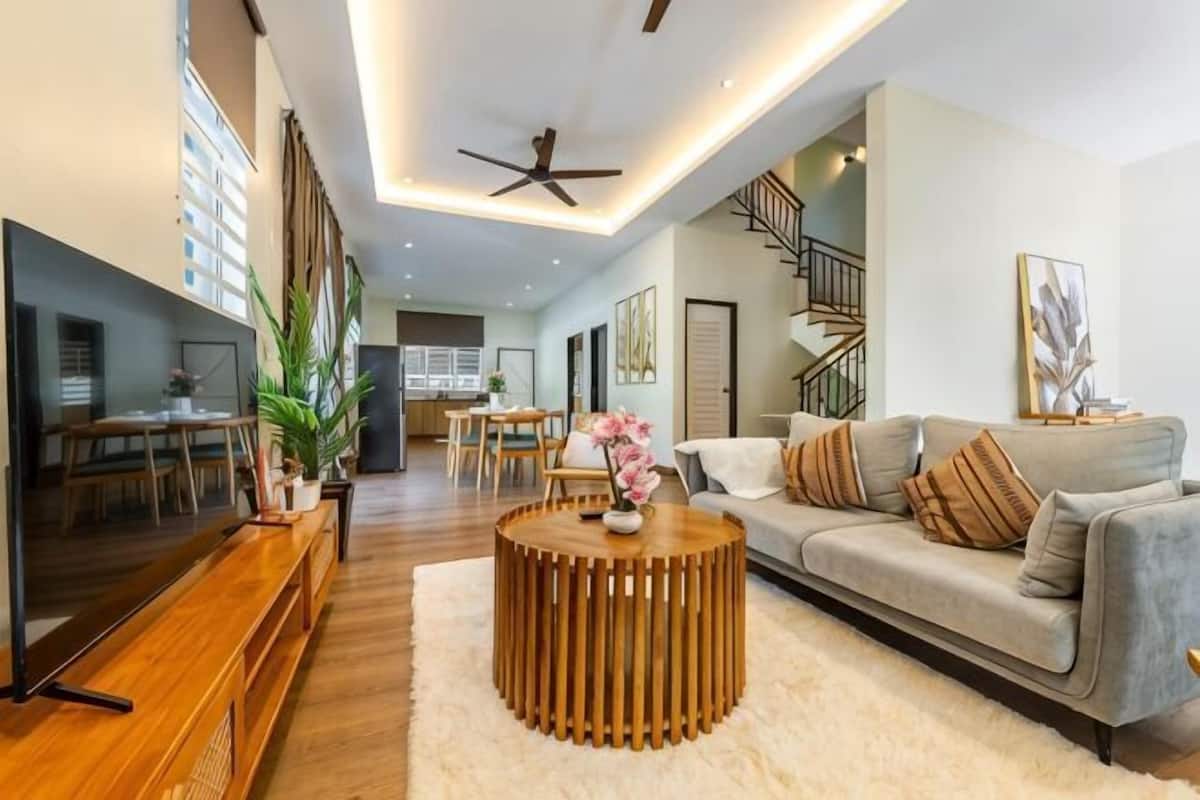 Ein modernes Wohnzimmer mit Sofa, Couchtisch, Fernseher und Treppe.