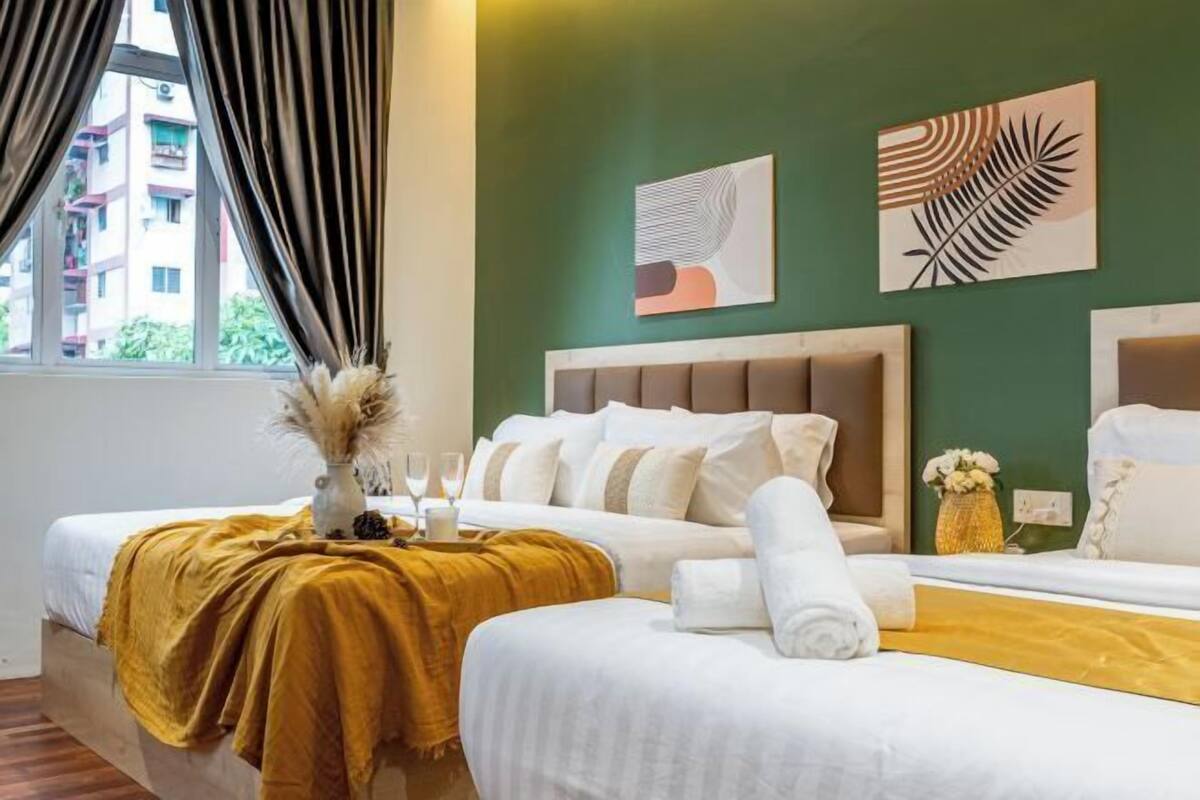 Ein Hotelzimmer mit zwei Betten, einer grünen Wand und Kunstwerken.