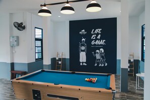 A pool table with a blue felt surface, a wall with a motivational quote, and a ceiling fan.