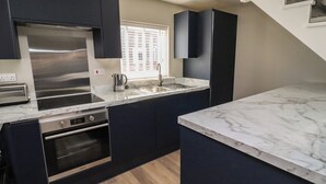 Una cocina moderna con armarios oscuros, electrodomésticos de acero inoxidable y una encimera de mármol.