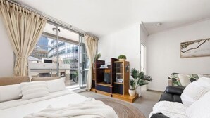 Moderni hotellihuone, jossa on suuri sänky, sohva, televisio ja kirjahylly.