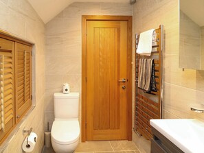 Un bagno con porta in legno, un water, un porta asciugamani e uno specchio.