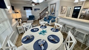 A dining area with a round table set for six, surrounded by white chairs. - 2 Golf Cart, 5 Bedroom Beach Escape, Ocean Lakes! (Myrtle Beach)