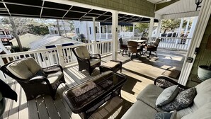 A covered outdoor seating area with wicker furniture and a glass table. - 2 Golf Cart, 5 Bedroom Beach Escape, Ocean Lakes! (Myrtle Beach)