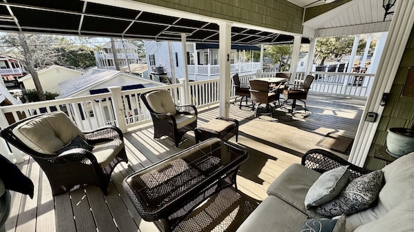 A covered outdoor seating area with wicker furniture and a glass table.