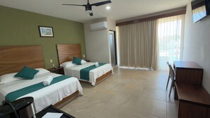 Une chambre d’hôtel avec deux lits, un bureau, une chaise, un ventilateur de plafond, un appareil de climatisation et une fenêtre avec des rideaux.