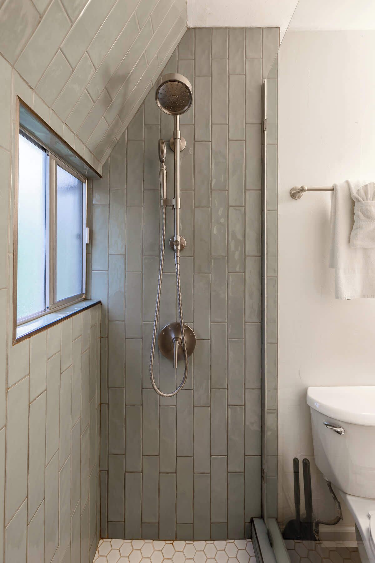 Une salle de bain avec une douche, des toilettes et une fenêtre.