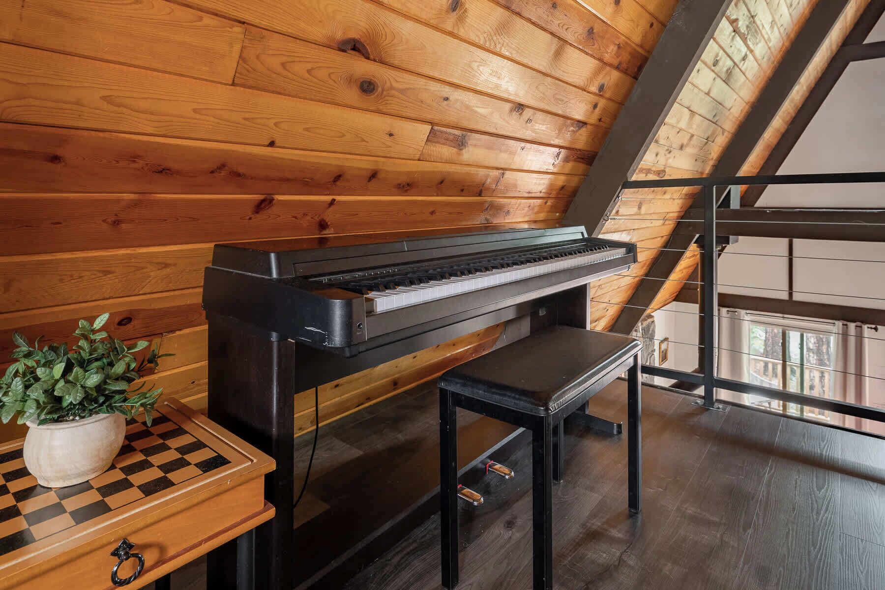 A piano in a room with wooden walls and a sloped ceiling.