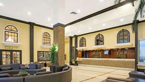 A spacious lobby with a reception desk, seating area, and a large plant.