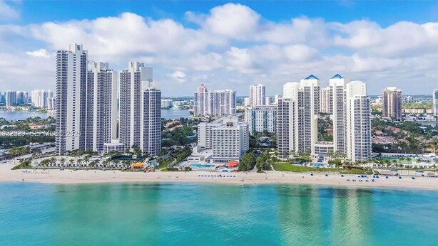 A coastal cityscape with high-rise buildings, a beach, and a marina.