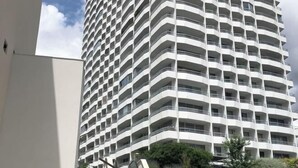 Un immeuble de grande hauteur doté d’une série de balcons disposés en réseau, d’un style architectural moderne, et avec un ciel dégagé en arrière-plan.
