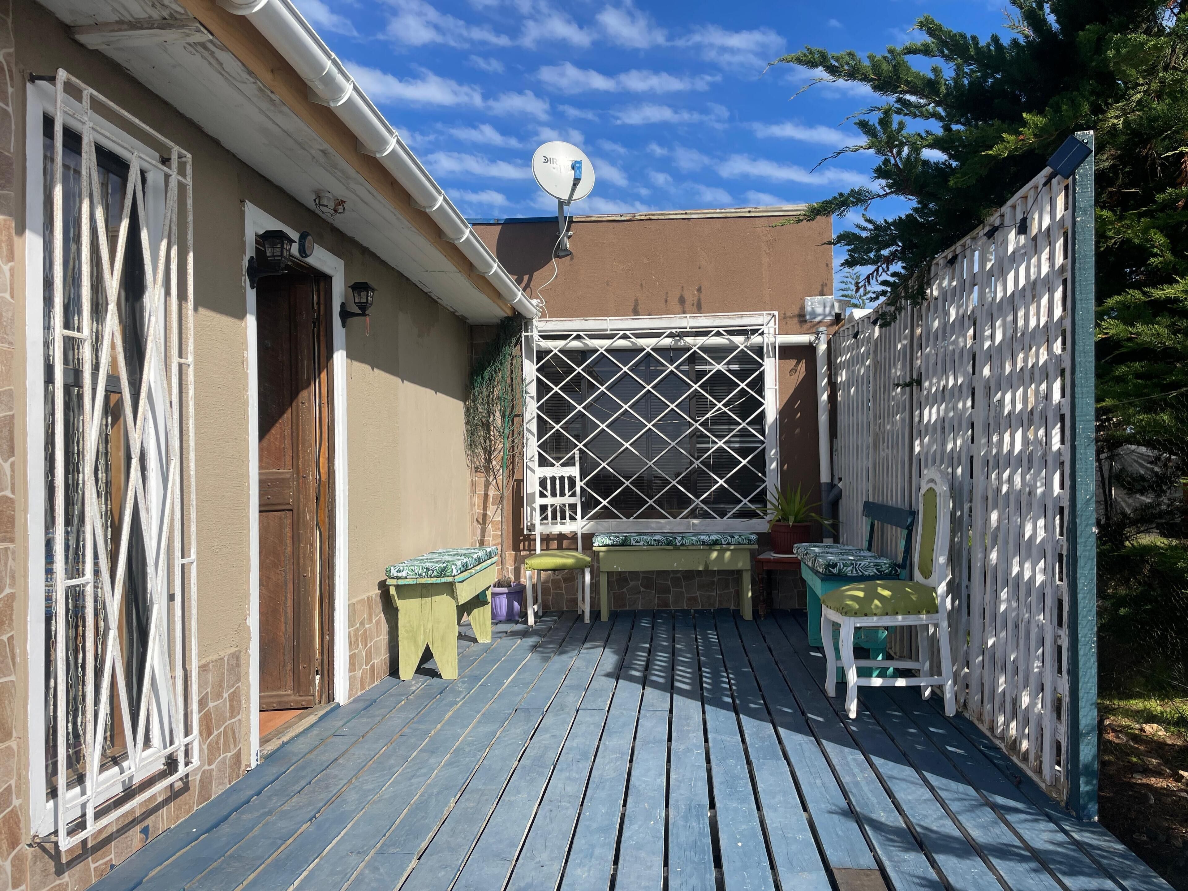 A wooden deck with a pergola, a small table, and two chairs.