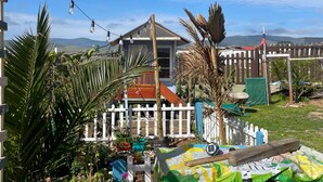 Un barrio residencial con una casa, cerca viva blanca y diversas plantas en macetas.