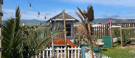 A residential area with a house, a white picket fence, and a variety of potted plants.