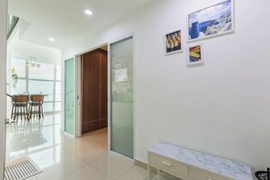 A modern interior with a glass door leading to a dining area, a marble bench, and artwork on the wall. - Maritime Seaview Comfy Suite in Penang with TVbox.Pool.Wifi (George Town)