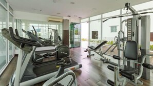 Academia com esteiras, máquinas de peso e um painel de espelhos.