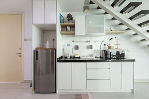 A modern kitchen with a built-in refrigerator, white cabinets, and a black countertop. - Maritime Seaview Comfy Suite in Penang with TVbox.Pool.Wifi (George Town)
