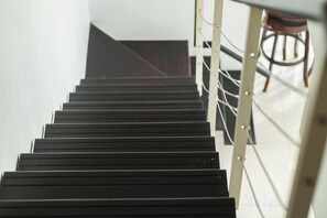 A staircase with a handrail and a chair in the background. - Maritime Seaview Comfy Suite in Penang with TVbox.Pool.Wifi (George Town)