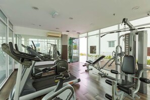 A gym with treadmills, weight machines, and a large window offering a view of the outdoors. - Maritime Seaview Comfy Suite in Penang with TVbox.Pool.Wifi (George Town)