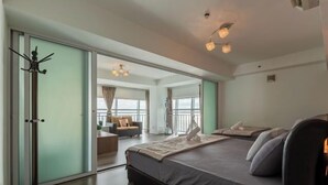 Quarto moderno com uma cama grande, um cabideiro e vista para uma varanda.
