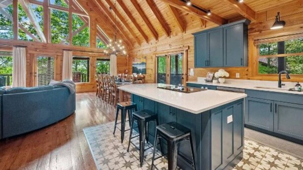 A spacious kitchen with a large island, wooden beams, and a view of the outdoors. - Rustic Cove: Views, Hot Tub, Theater & Game Room! (Sevierville)