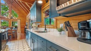 A modern kitchen with dark cabinets, a large island, and a Keurig coffee maker. - Rustic Cove: Views, Hot Tub, Theater & Game Room! (Sevierville)