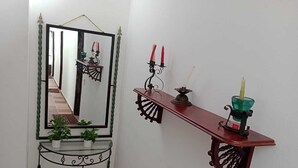A hallway with a mirror, a small table with potted plants, a decorative shelf with candles, and a green glass candle holder. - CASA DE CAMPO PRIVADA CON PISCINA (La Mesa)